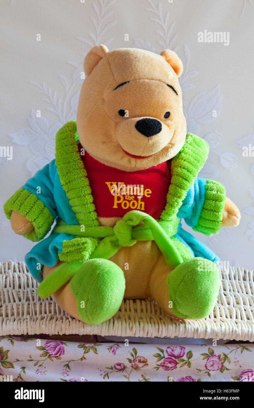 Winnie l'Ourson doux jouet cudly portant robe de chambre et pantoufles assis sur un panier en osier Banque D'Images