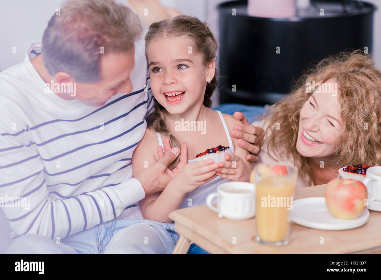 Little girl holding cupcake berry et rire avec ses grands-parents Banque D'Images