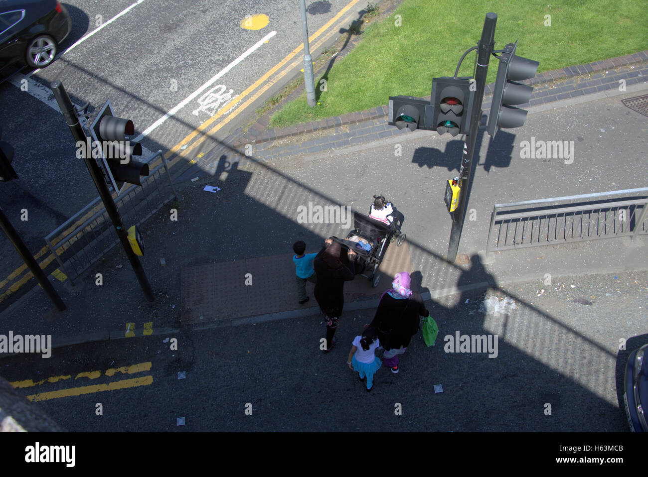 Famille d'immigrants sur la chaussée près de feux de circulation, Glasgow, Ecosse Banque D'Images