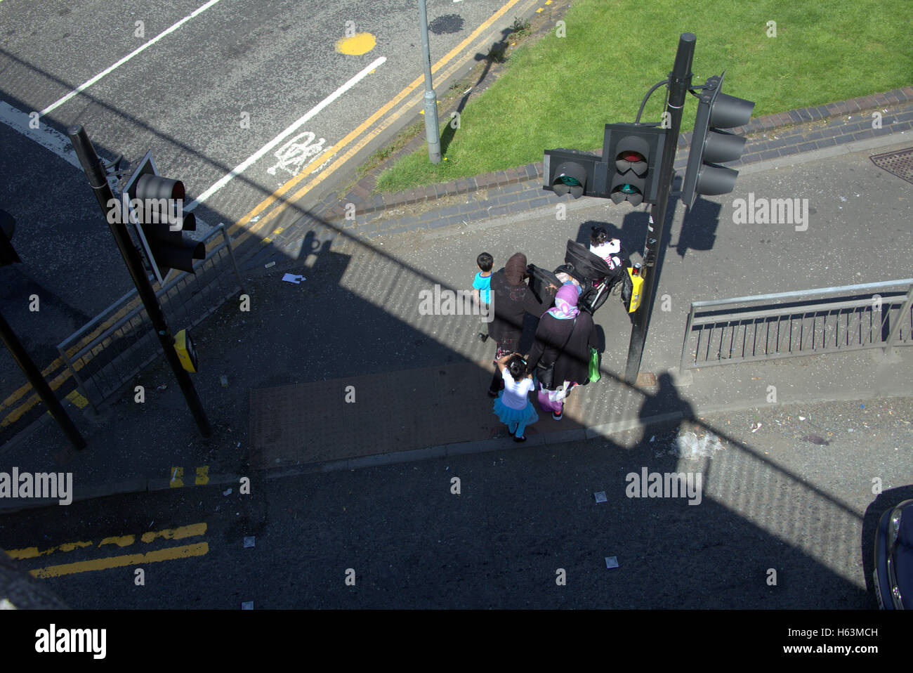 Famille d'immigrants sur la chaussée près de feux de circulation, Glasgow, Ecosse Banque D'Images