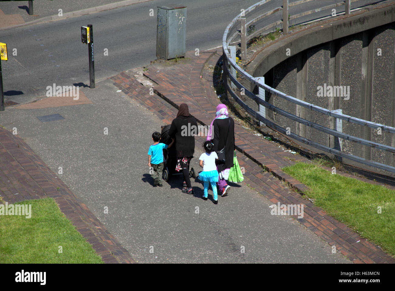 Famille d'immigrants sur la chaussée près de feux de circulation, Glasgow, Ecosse Banque D'Images
