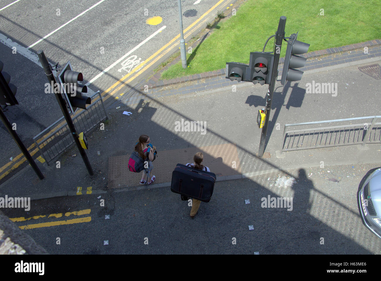 Les gens près de la chaussée valise sur les feux de circulation, Glasgow, Ecosse Banque D'Images