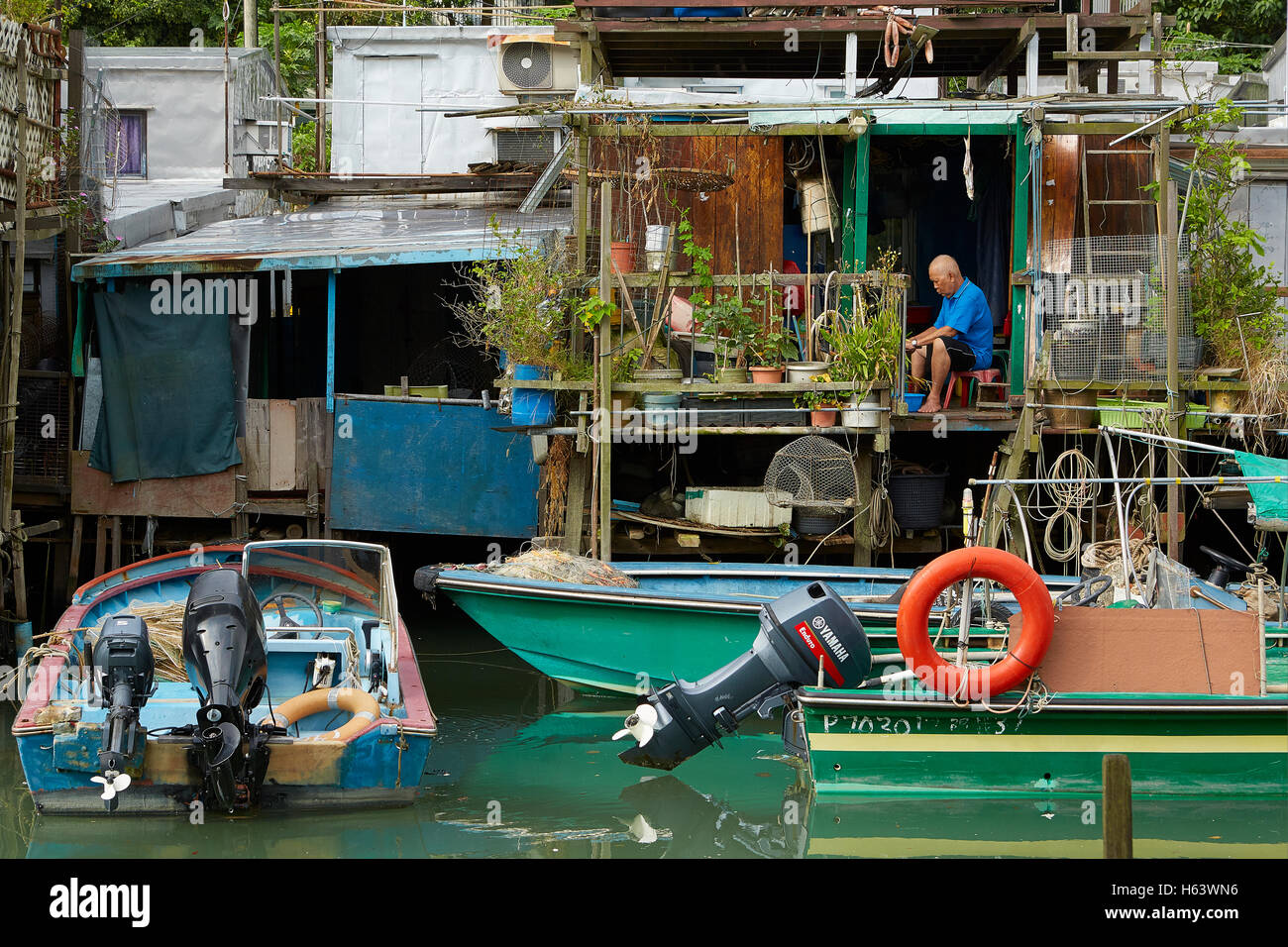 Personnes âgées chinois travaillant sur son balcon à Tai O, un village de pêcheurs Oriental Sur l'île de Lantau, à Hong Kong. Banque D'Images
