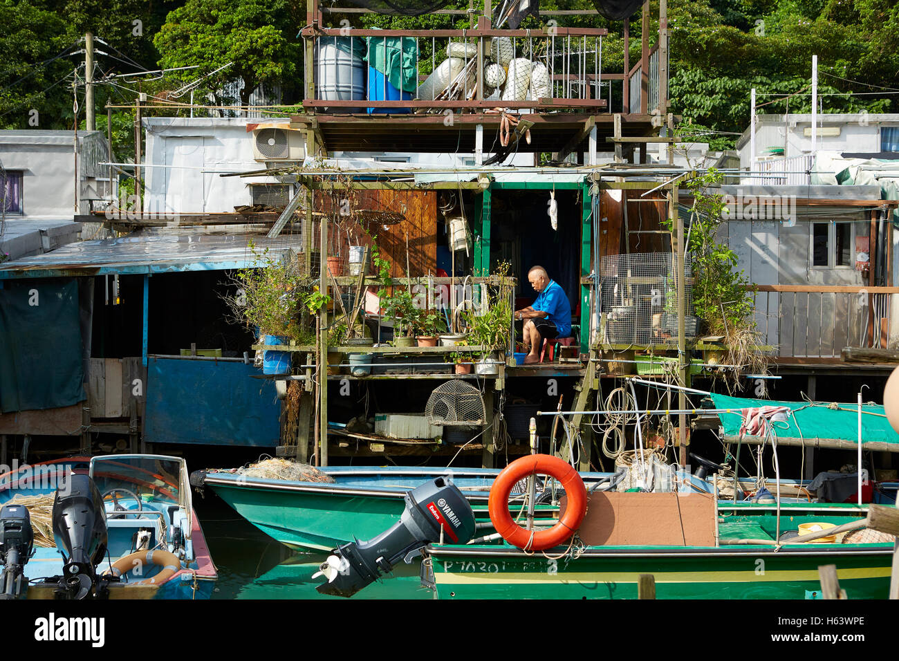 Personnes âgées chinois travaillant sur son balcon à Tai O, un village de pêcheurs Oriental Sur l'île de Lantau, à Hong Kong. Banque D'Images