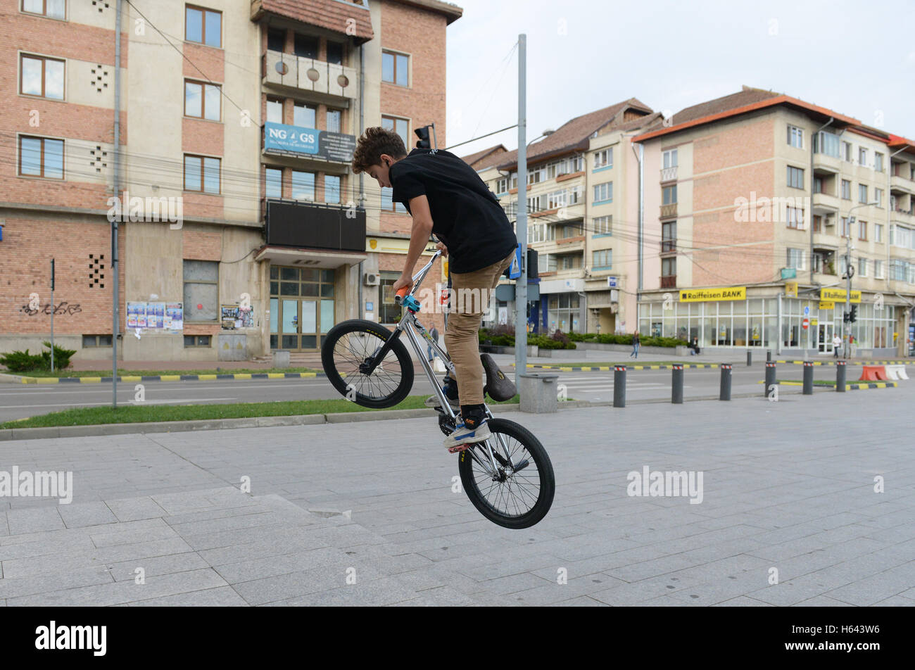 Un jeune garçon roumain pratiquant cascades sur son vélo dans le centre de Suceava, Roumanie. Banque D'Images