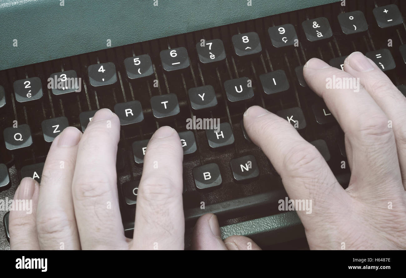 Mains saisissant les clés sur une vieille machine à écrire. Banque D'Images