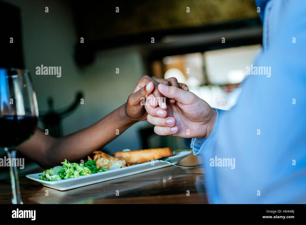 Close-up of a couple holding hands in restaurant Banque D'Images