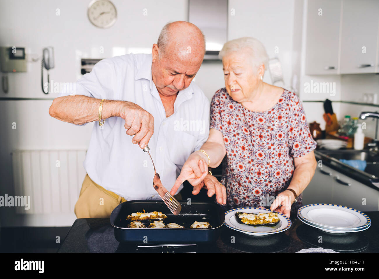 Senior couple servant dans la cuisine des aubergines farcies Banque D'Images