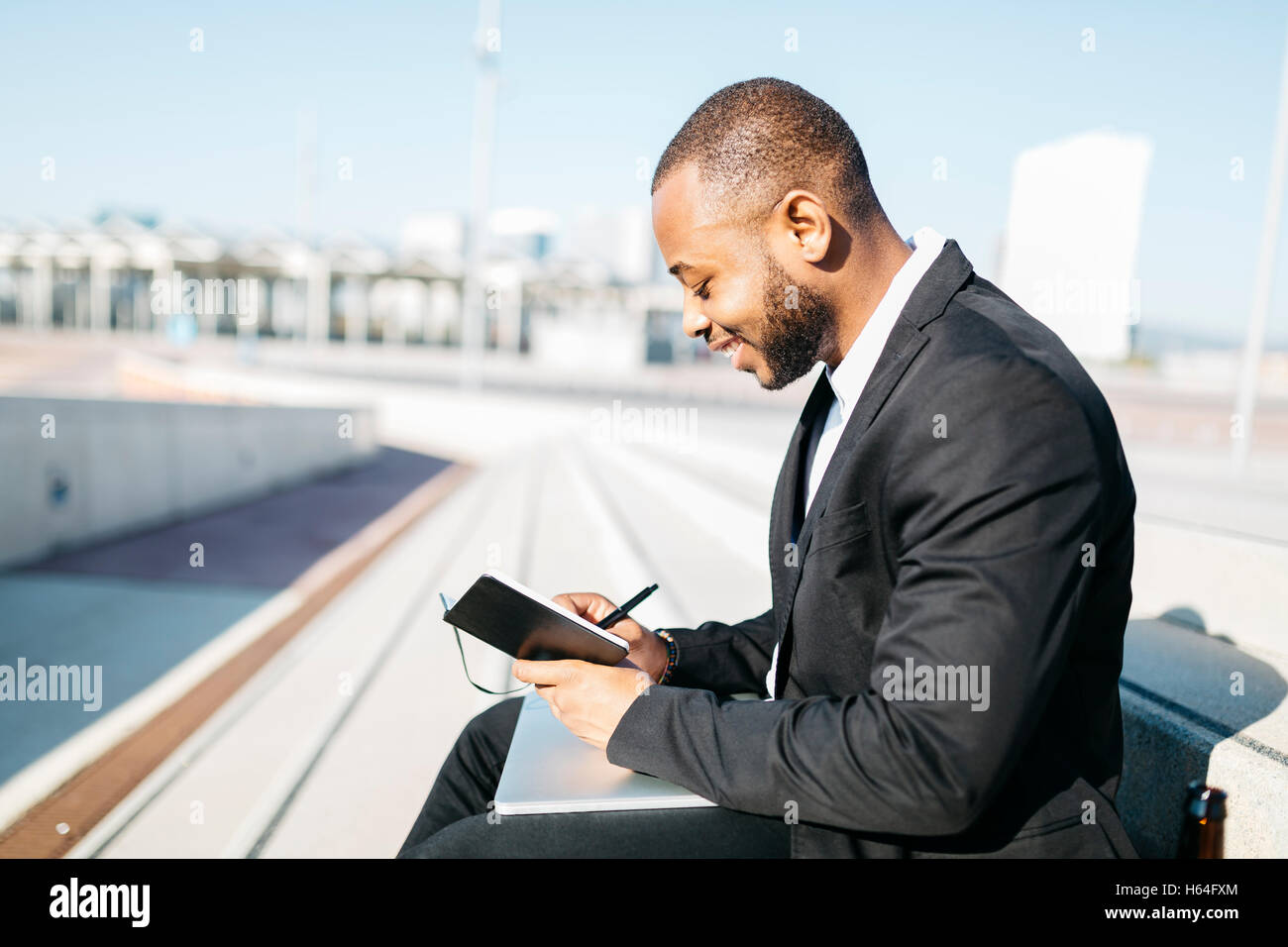 Smiling businessman writing in notebook Banque D'Images