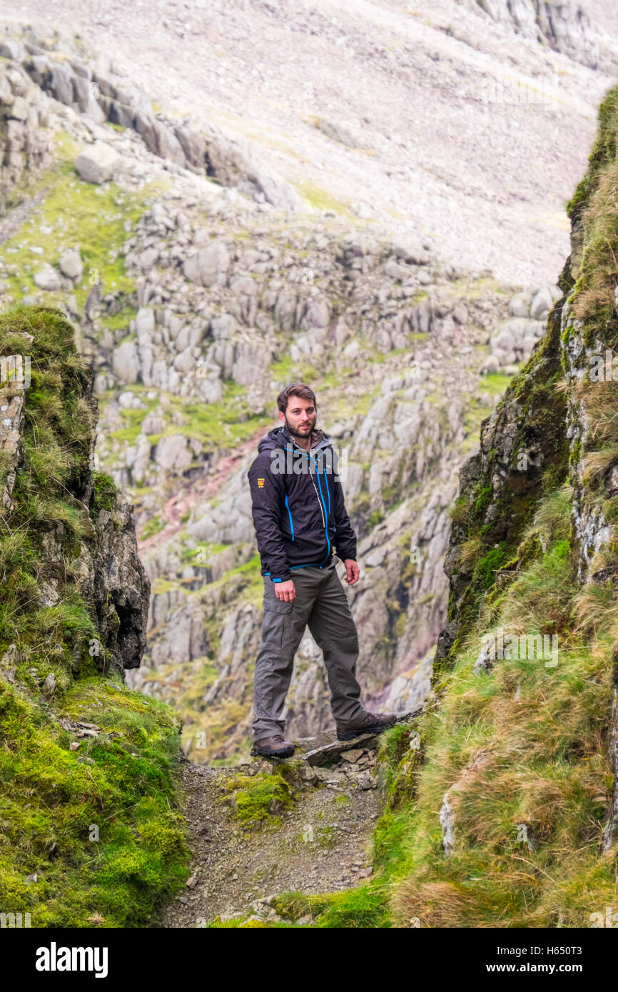 Homme dans la mi-vingtaine randonnées dans le Lake District, vêtu d'une veste. Paramo Le râteau du Seigneur, au coeur du lac Banque D'Images