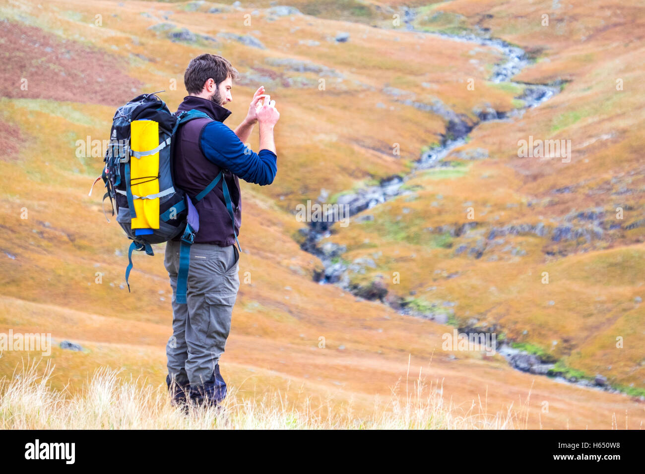 Homme dans la mi-vingtaine randonnées dans le Lake District, prendre une photo avec un téléphone intelligent Banque D'Images