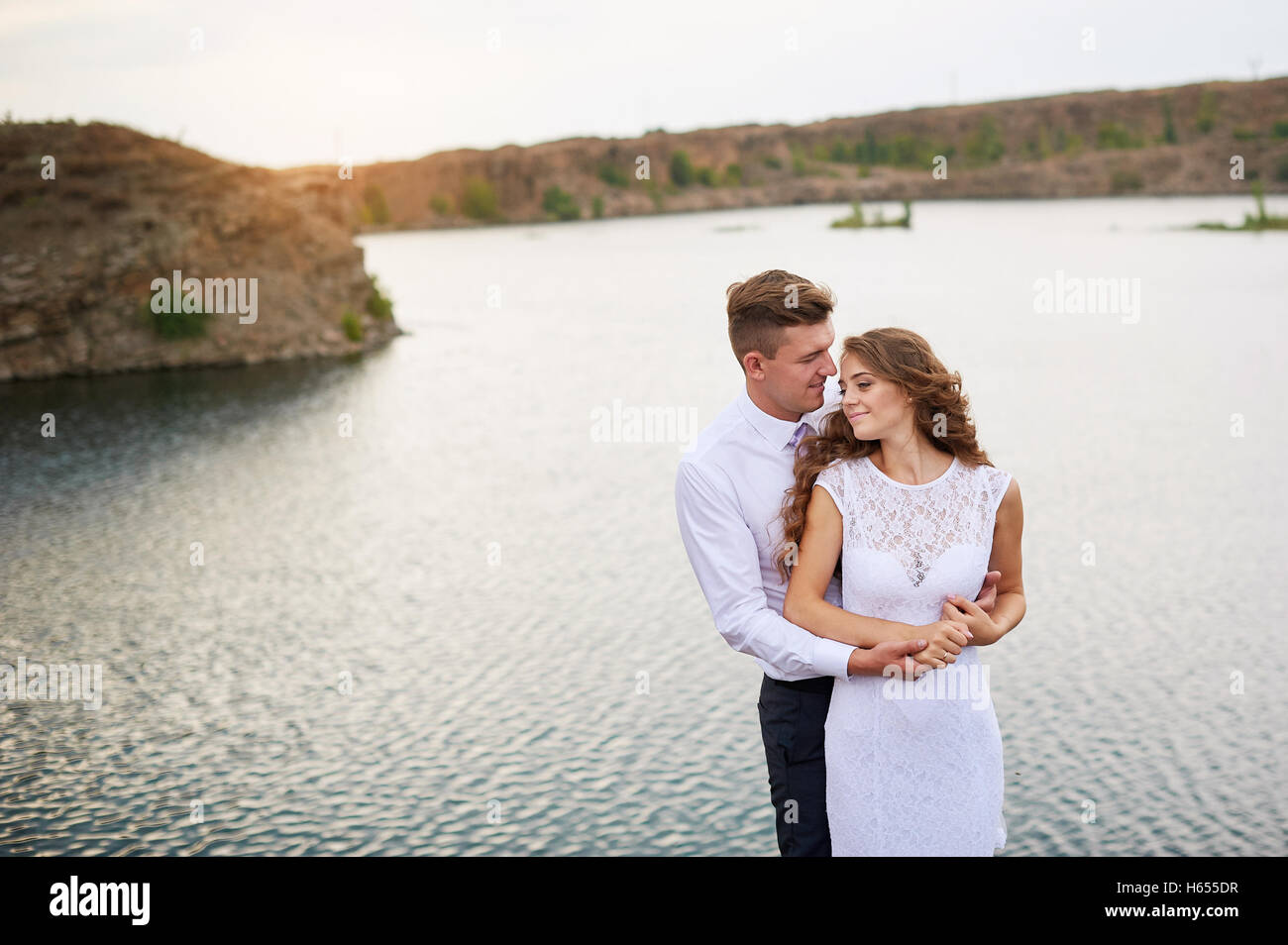 Beau couple de jeunes mariés à pied mariage au bord du lac Banque D'Images