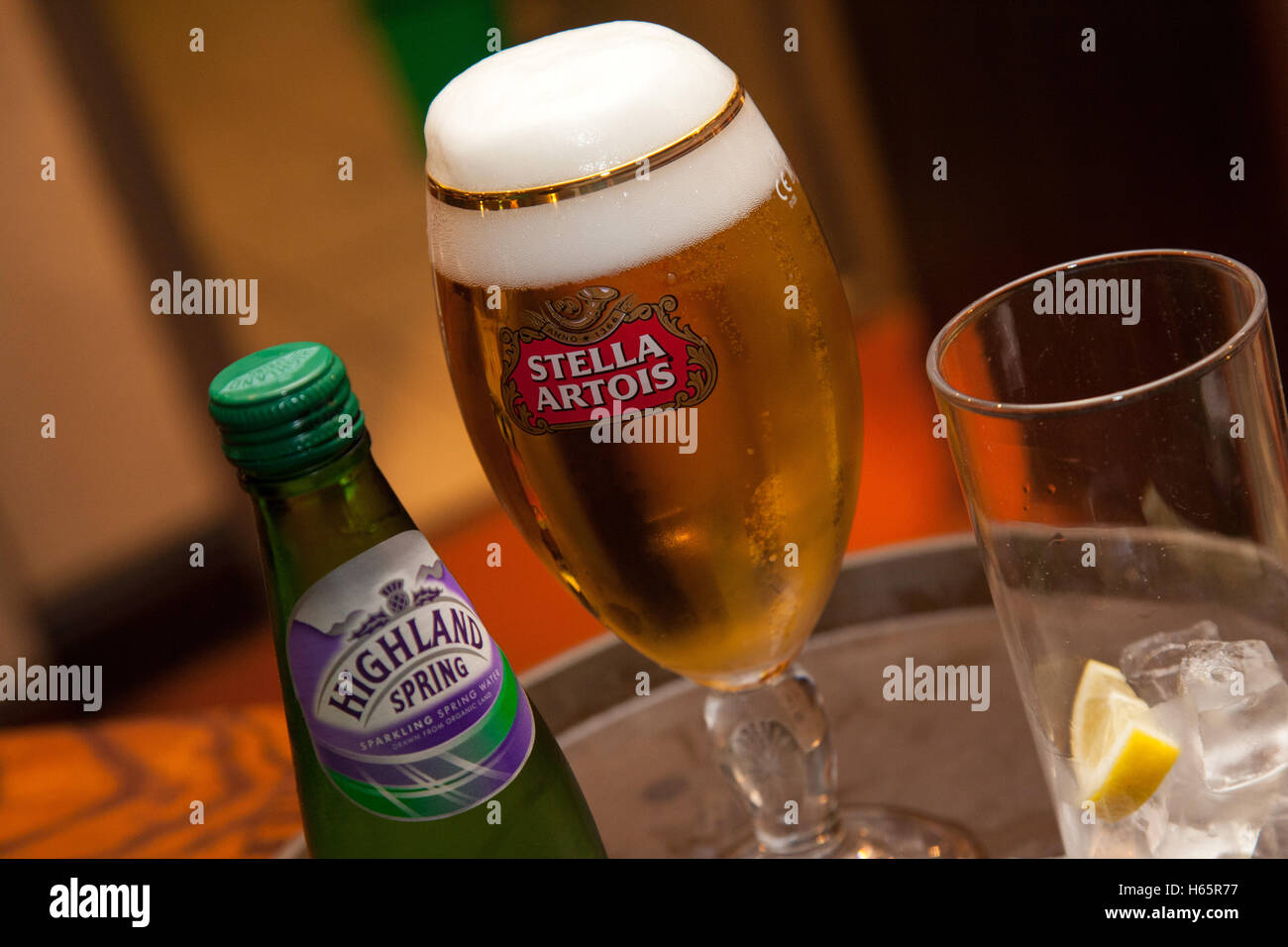 Verre de bière Stella Artois, et des hautes terres de l'eau de source, avec de la glace sur un plateau de pub Banque D'Images
