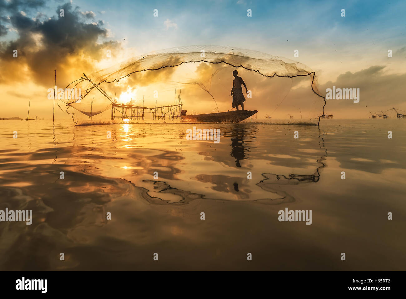 Pêcheur de bateau en bois, qui jetaient un filet pour attraper les poissons. Filet de pêche pêcheur de pierres pendant le lever du soleil à Pak Pra, Phatthalung Banque D'Images