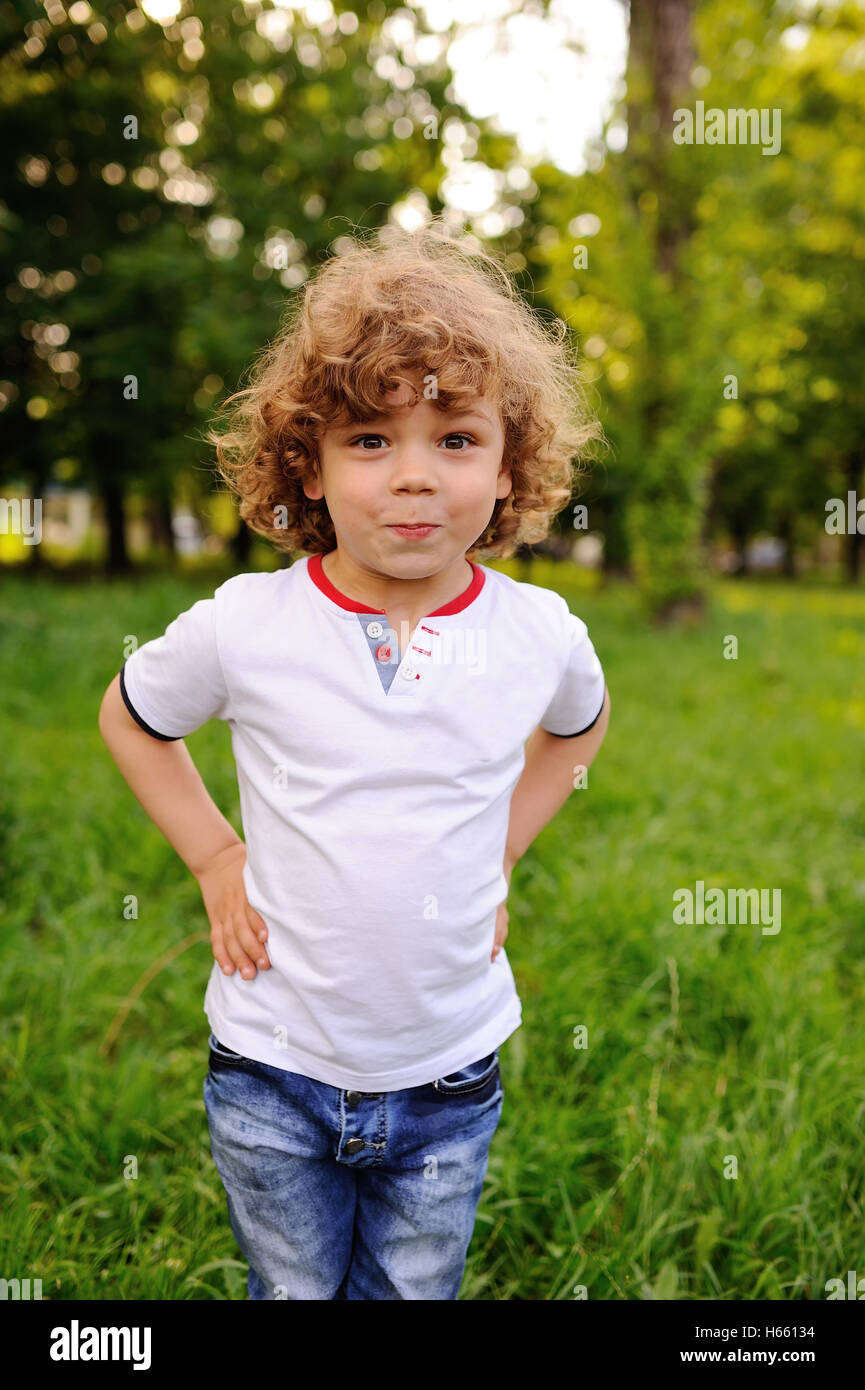 Bébé garçon avec les cheveux bouclés sur un fond de verdure Photo Stock -  Alamy