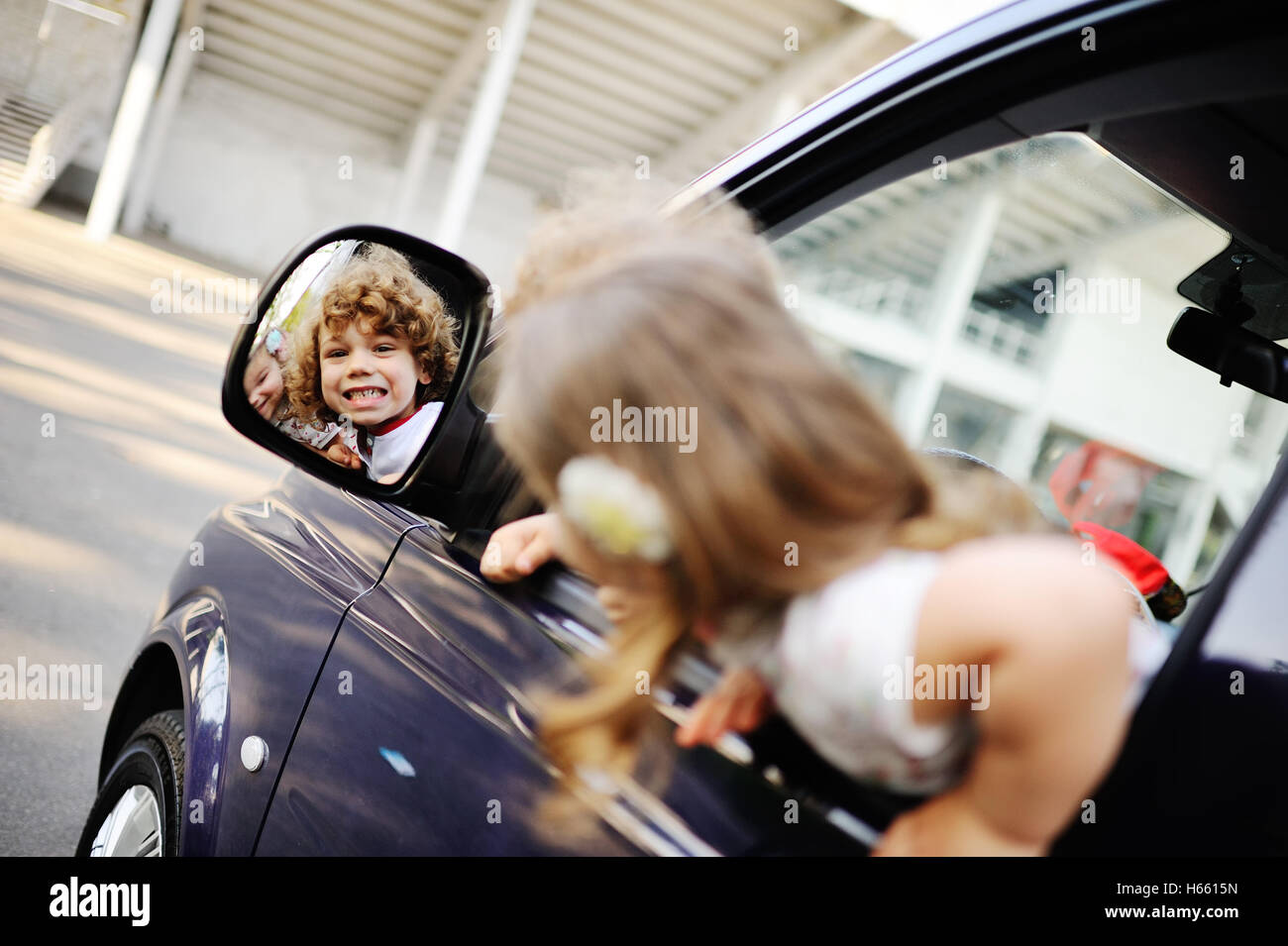 Les enfants donnent de la fenêtre d'une voiture Banque D'Images