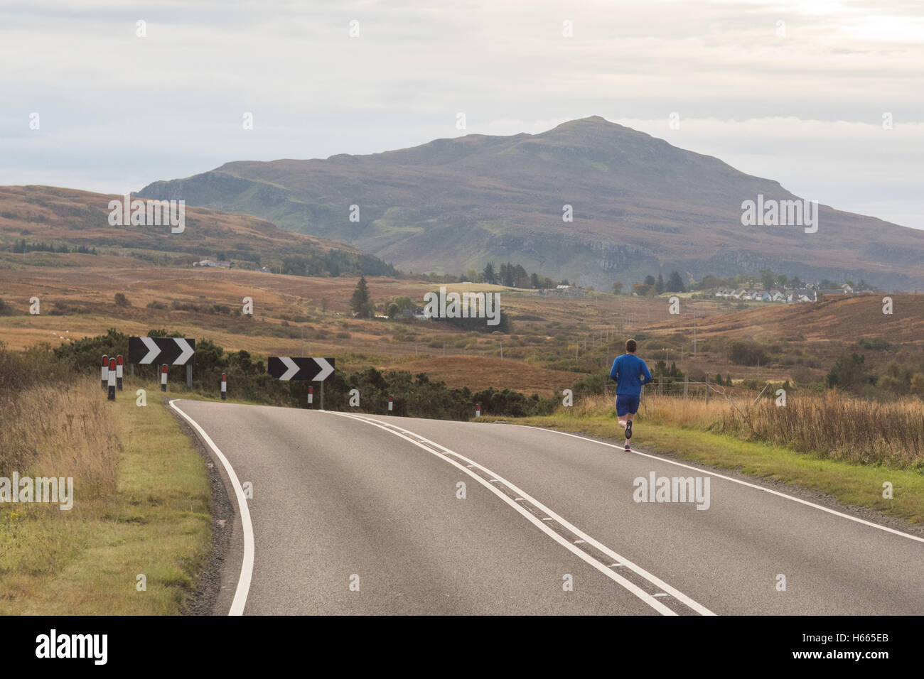 Homme qui court le long d'une route sur l'île de Skye en automne, Ecosse, Royaume-Uni Banque D'Images