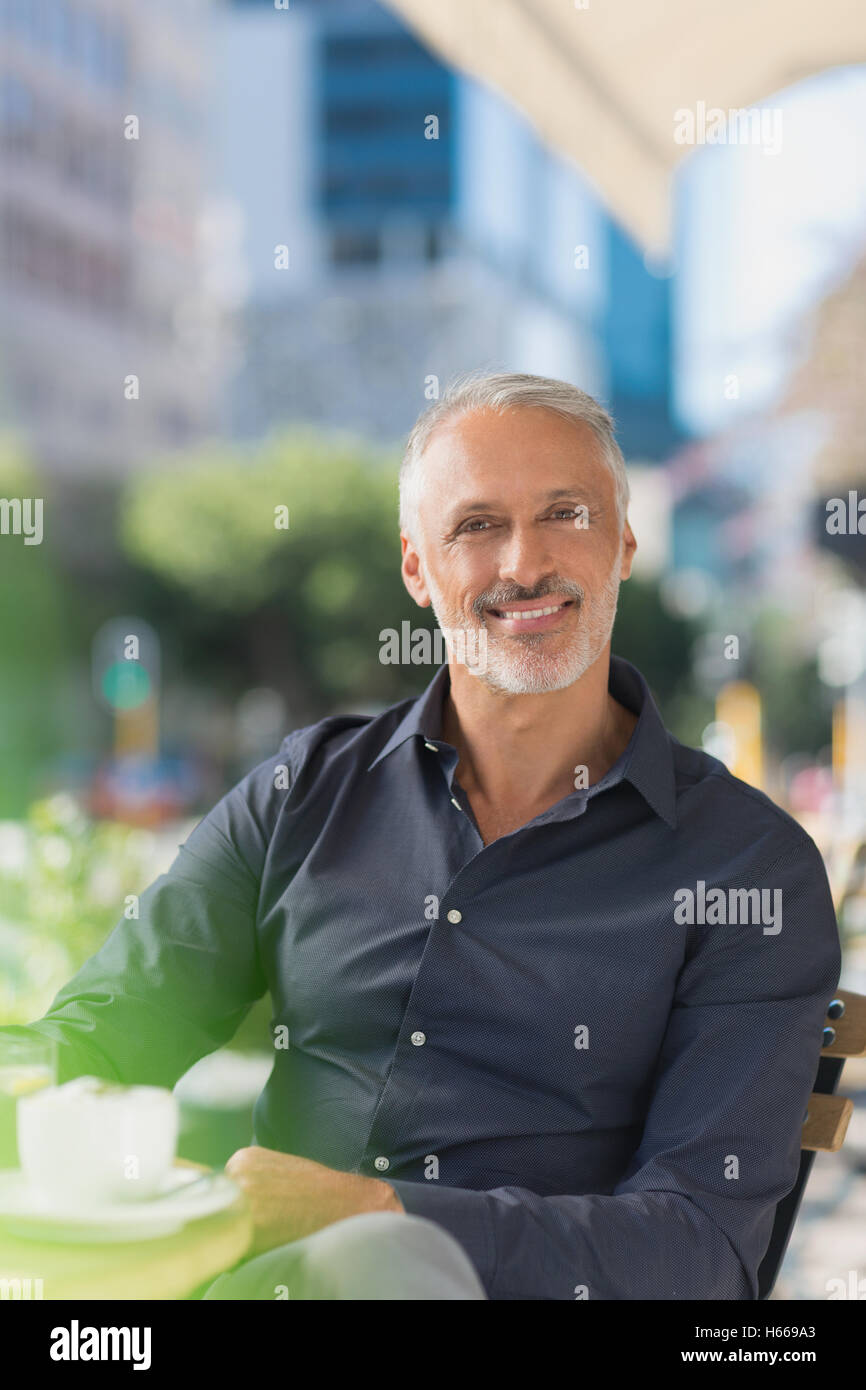 Portrait of smiling man drinking coffee at sidewalk cafe urbain Banque D'Images