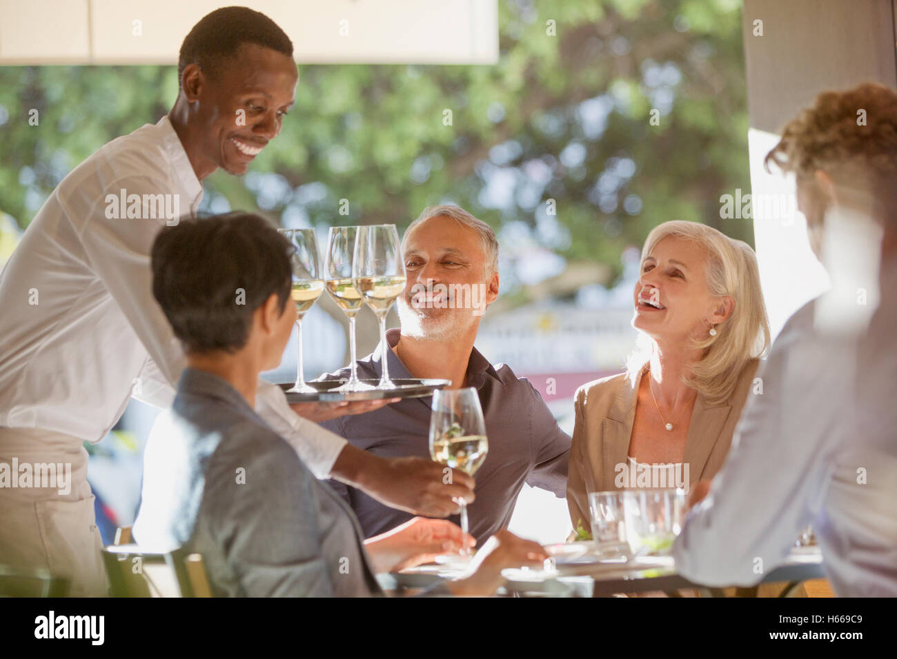 Waiter serving vin blanc à des couples au restaurant table Banque D'Images