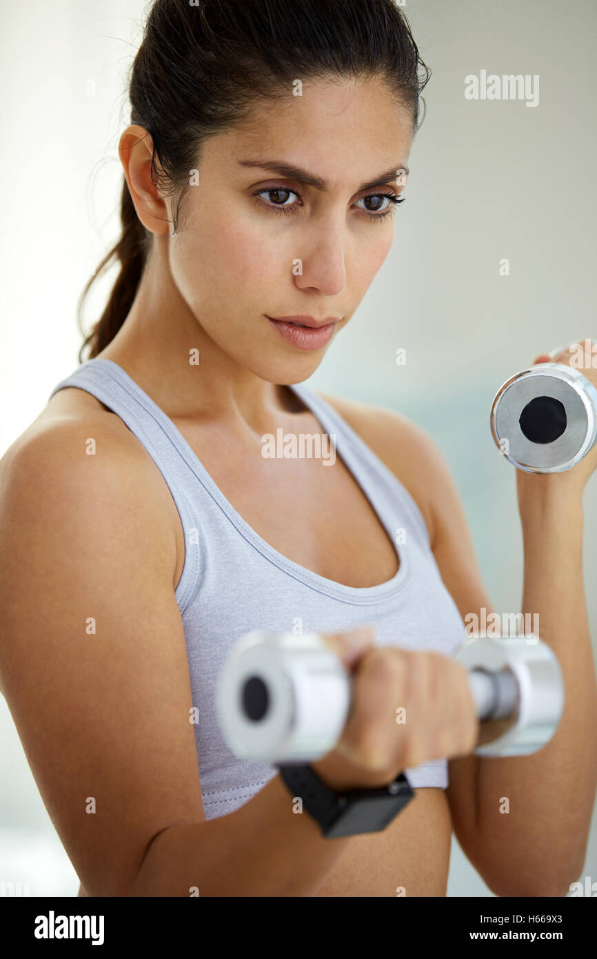 Déterminé brunette woman faisant de biceps avec haltères Banque D'Images