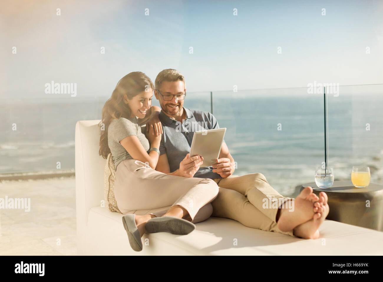Man using digital tablet on sunny luxe balcon avec vue sur l'océan Banque D'Images