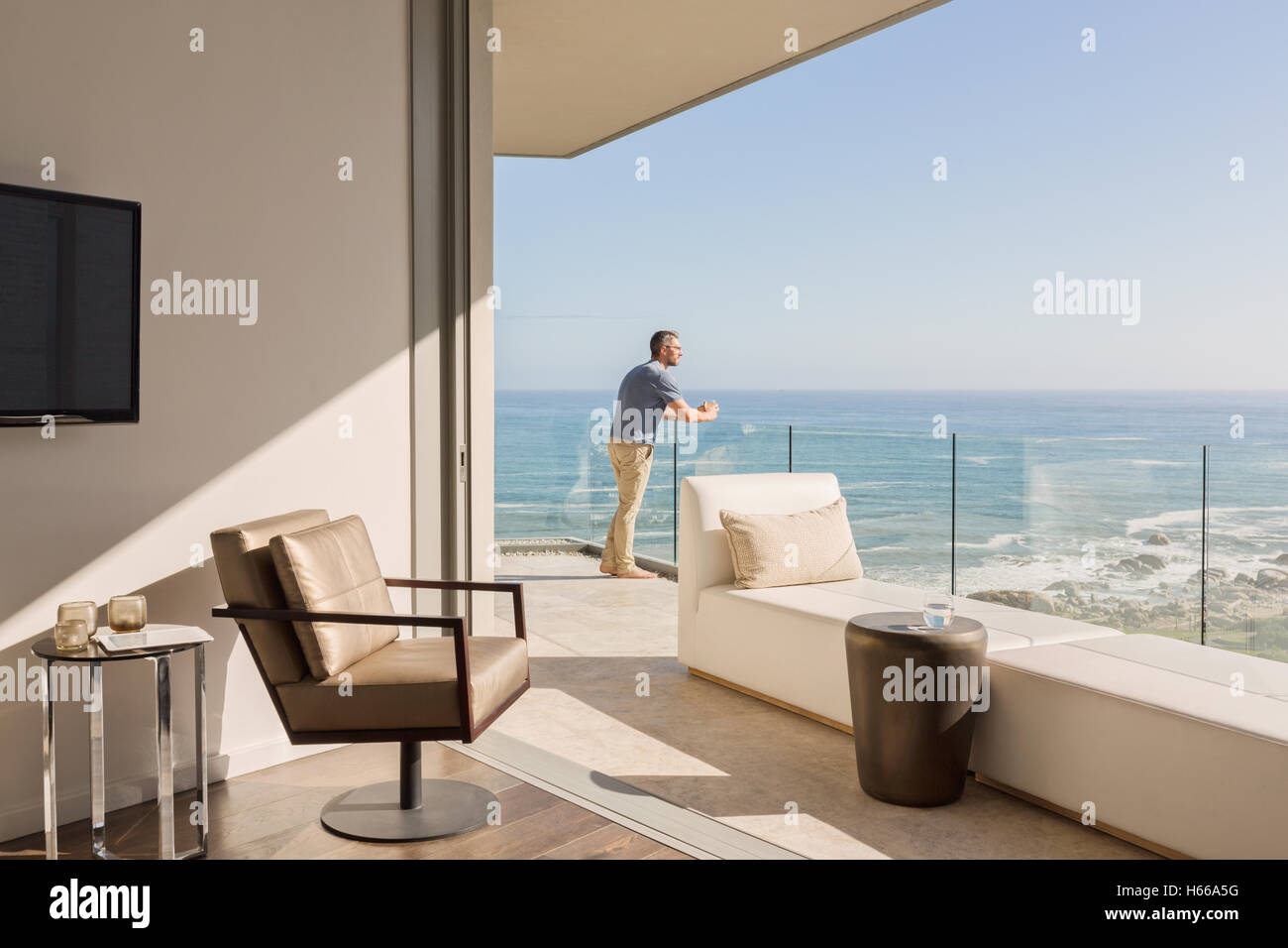 Man enjoying sunny luxe Balcon vue mer à partir de Banque D'Images