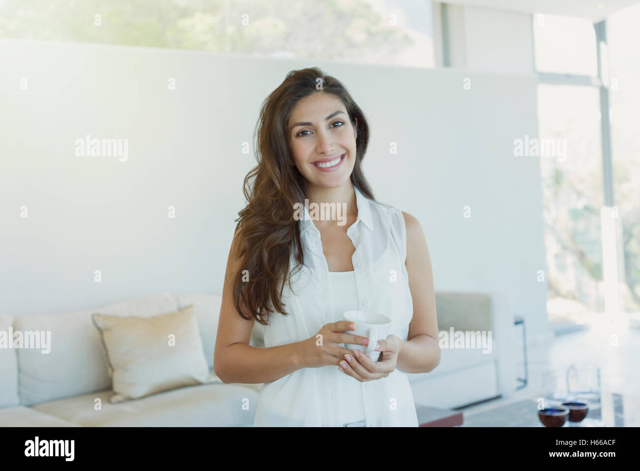 Portrait of smiling woman drinking coffee in living room Banque D'Images