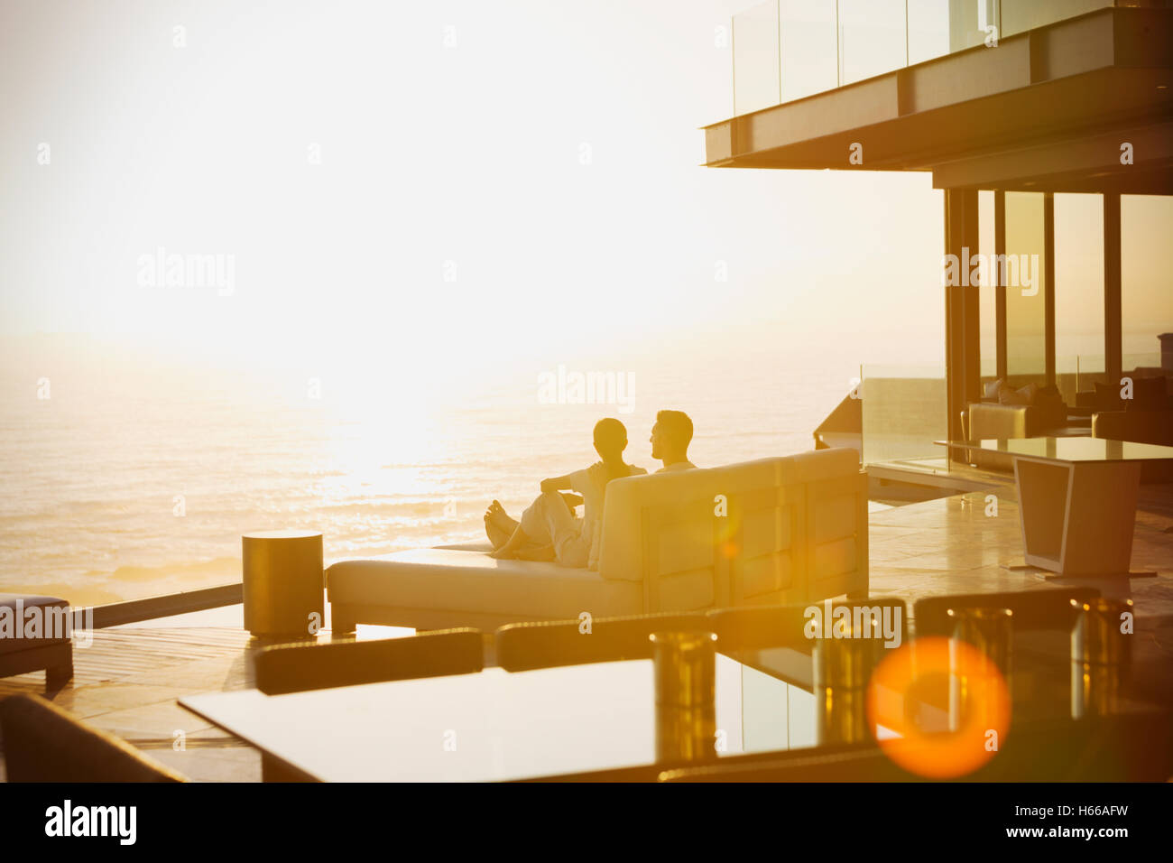 Silhouette couple relaxing on chaise longue profitant de coucher du soleil sur l'océan Banque D'Images