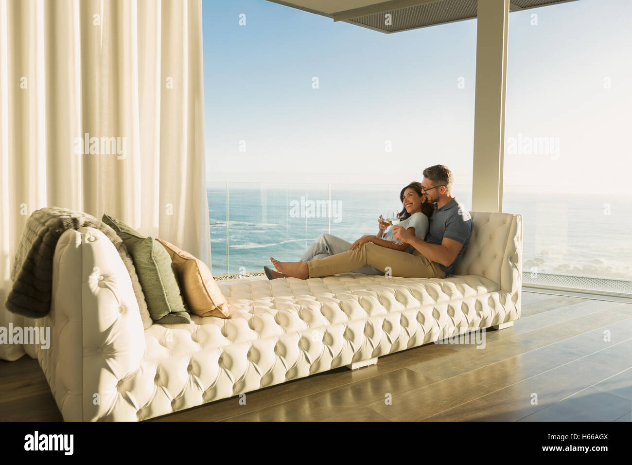 Affectionate couple boire du vin produit sur sur une chaise longue avec vue sur l'océan Banque D'Images