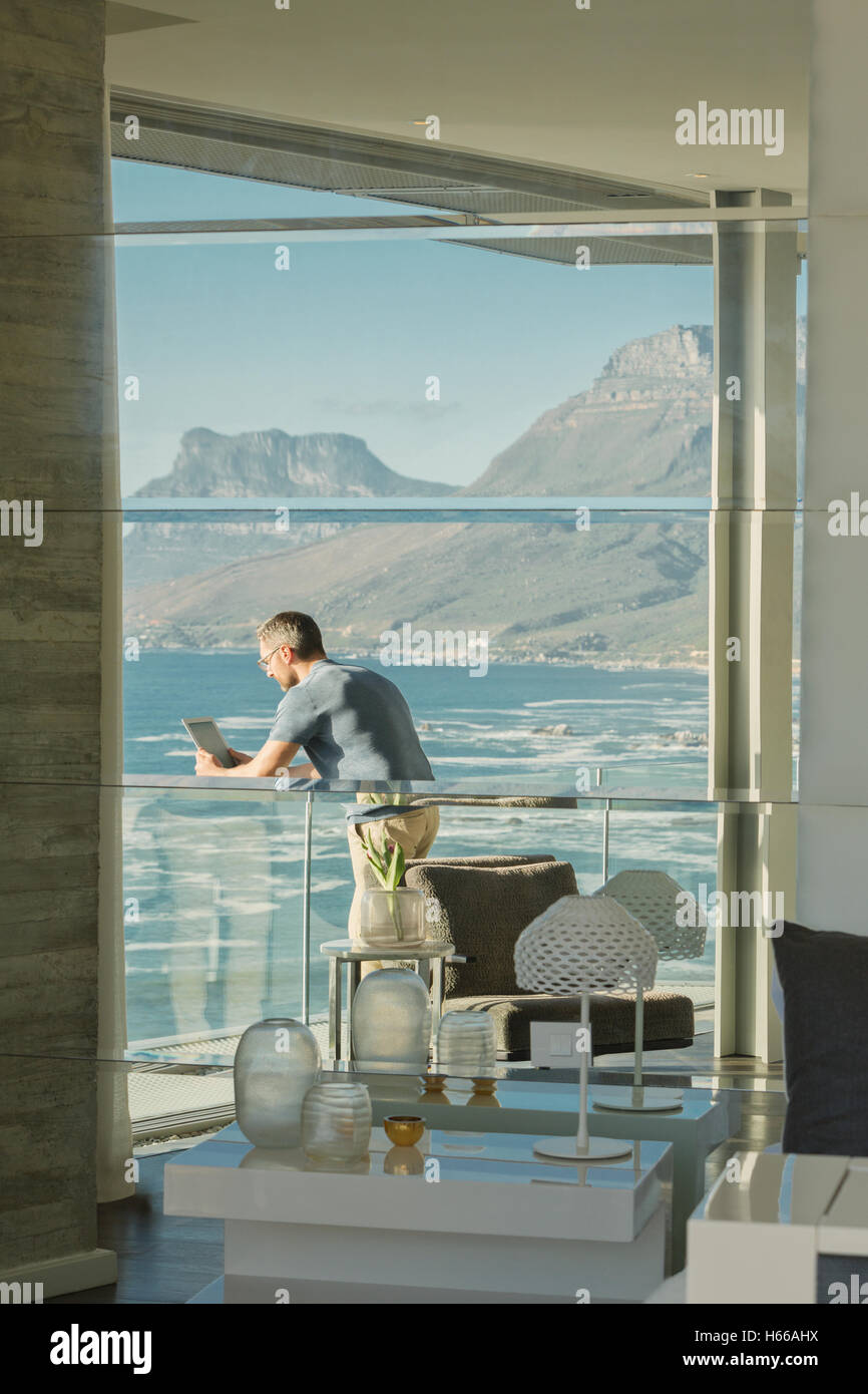 La réflexion de l'homme à l'aide de tablette numérique sur le luxe de l'océan et balcon avec vue sur la montagne Banque D'Images