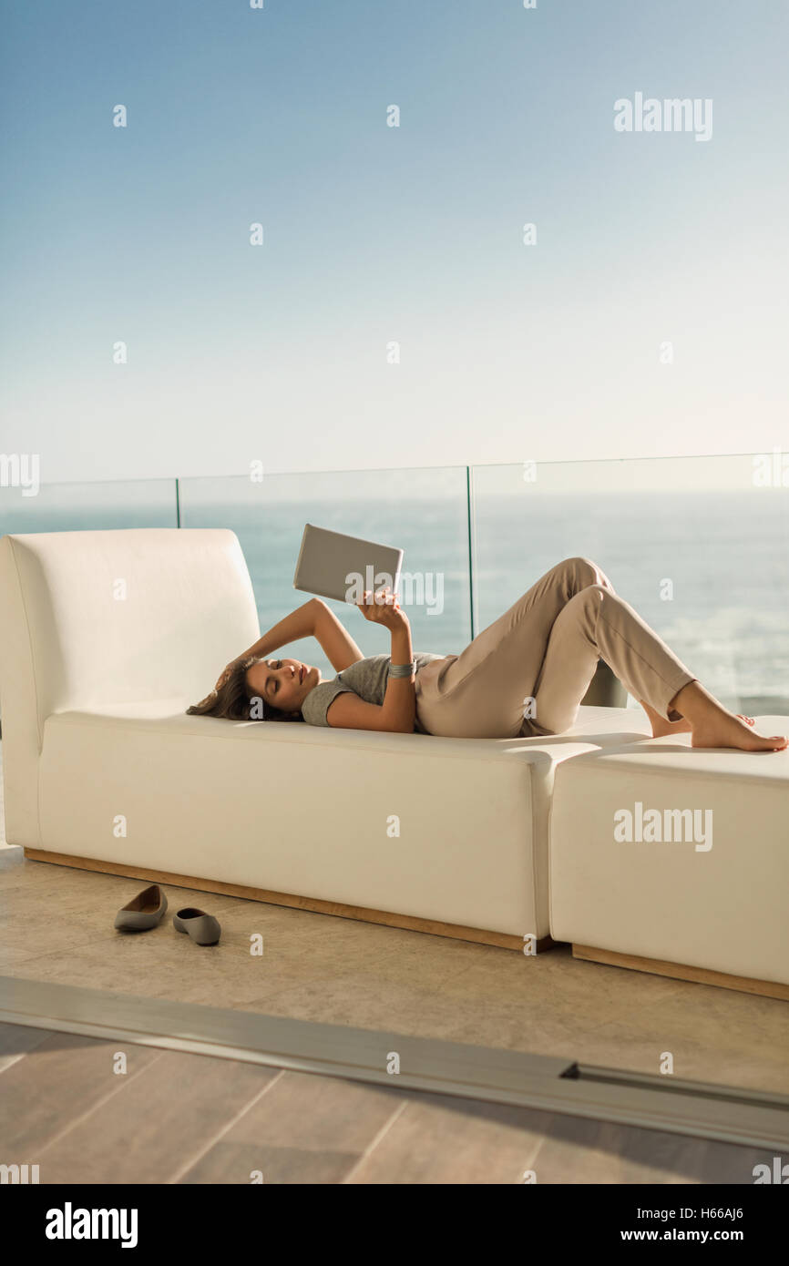 Woman using digital tablet pose détente sur une chaise longue sur le balcon avec vue sur l'océan de luxe Banque D'Images