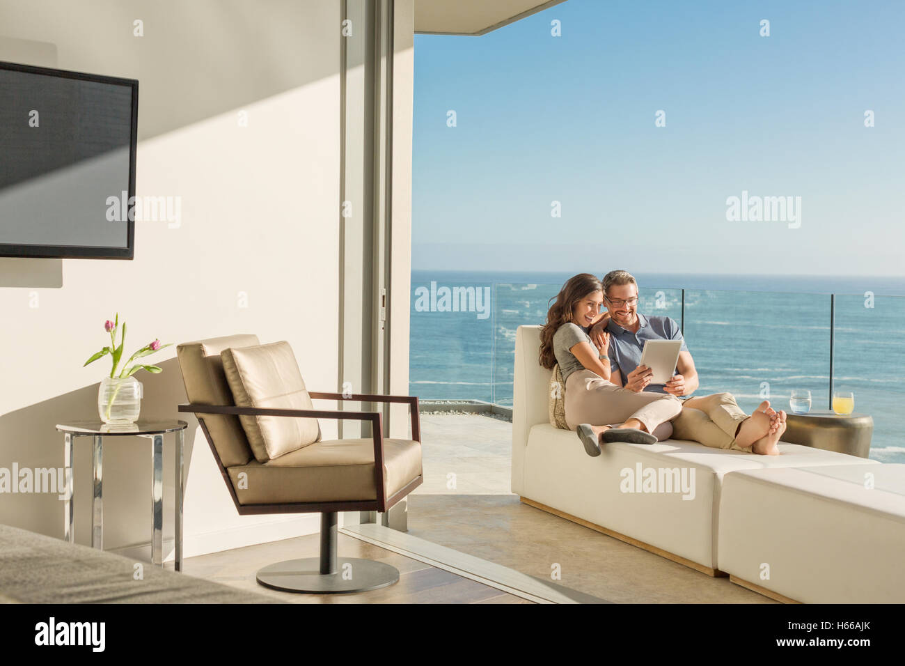 Couple sur une chaise longue sur le balcon ensoleillé avec vue sur l'océan de luxe Banque D'Images
