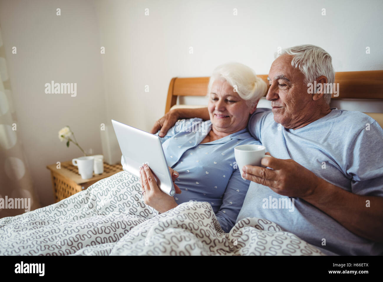 Senior woman using digital tablet et l'homme ayant tasse de café Banque D'Images