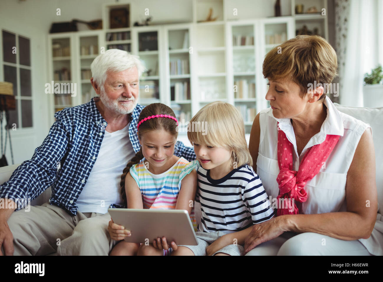 Petits-enfants à l'aide de tablette numérique avec leurs grands-parents Banque D'Images
