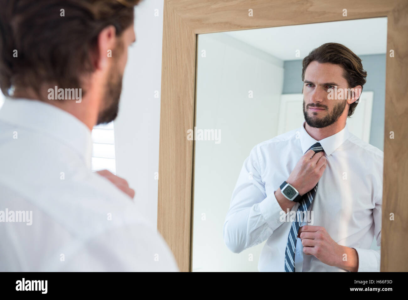L'homme s'habiller dans la chambre tout en regardant mirror Banque D'Images
