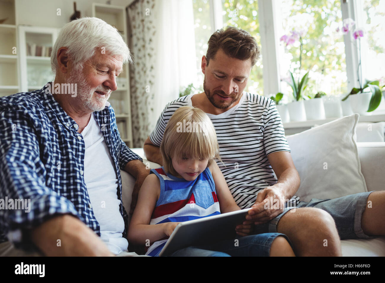 Boy using digital tablet avec son père et son grand-père dans la salle de séjour Banque D'Images