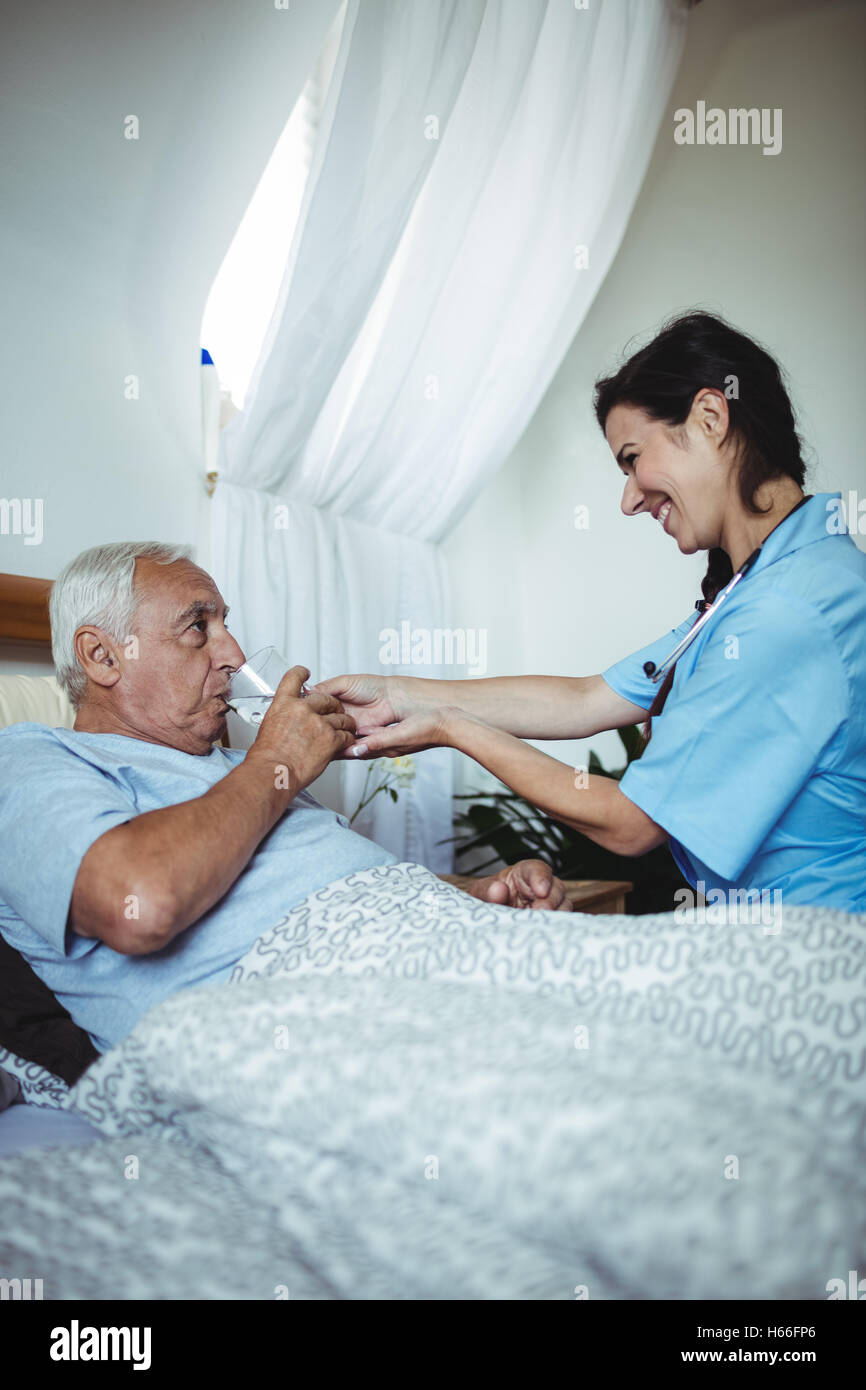 Infirmière en donnant un verre d'eau à man Banque D'Images