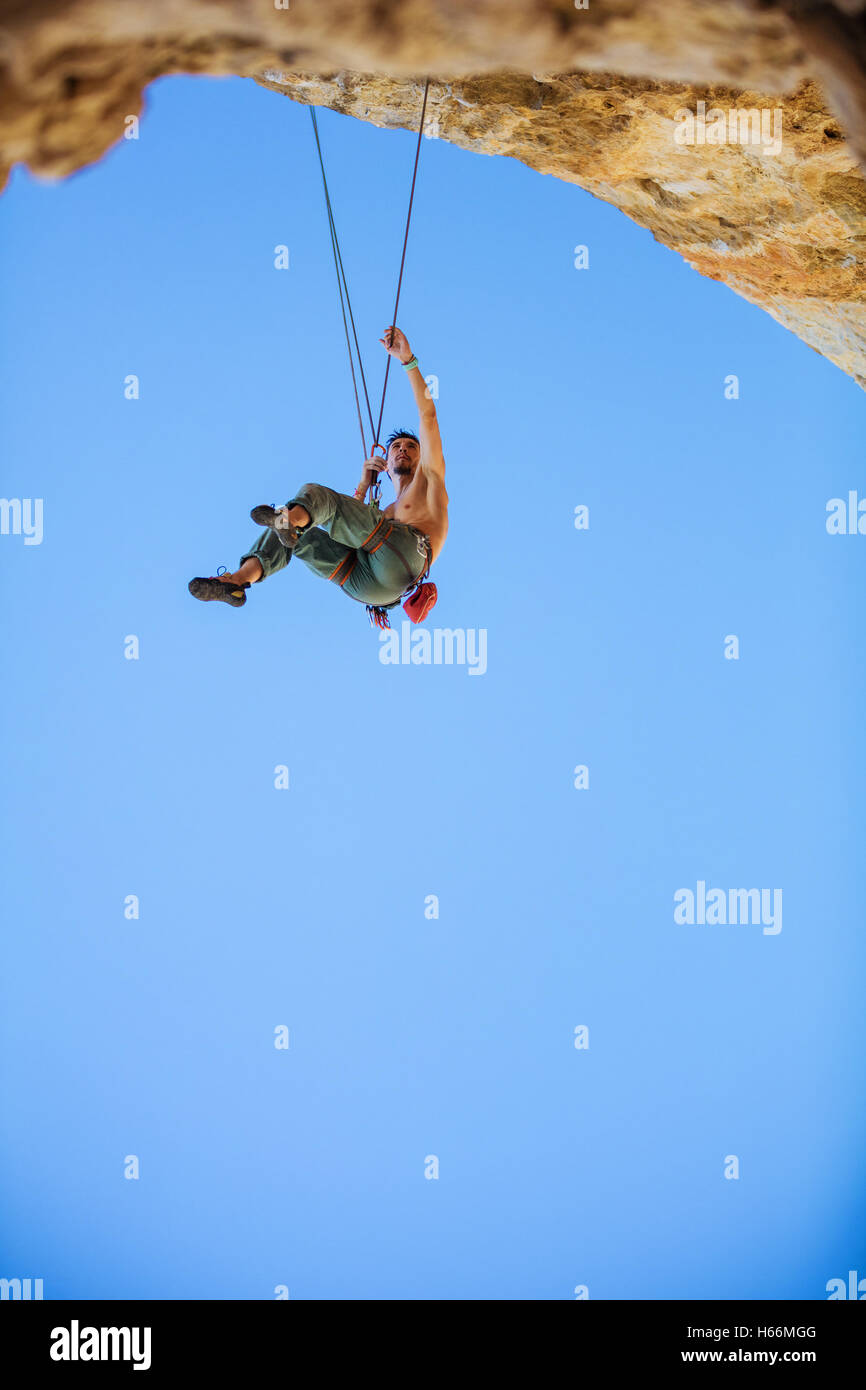 Male rock climber hanging sur corde Banque D'Images