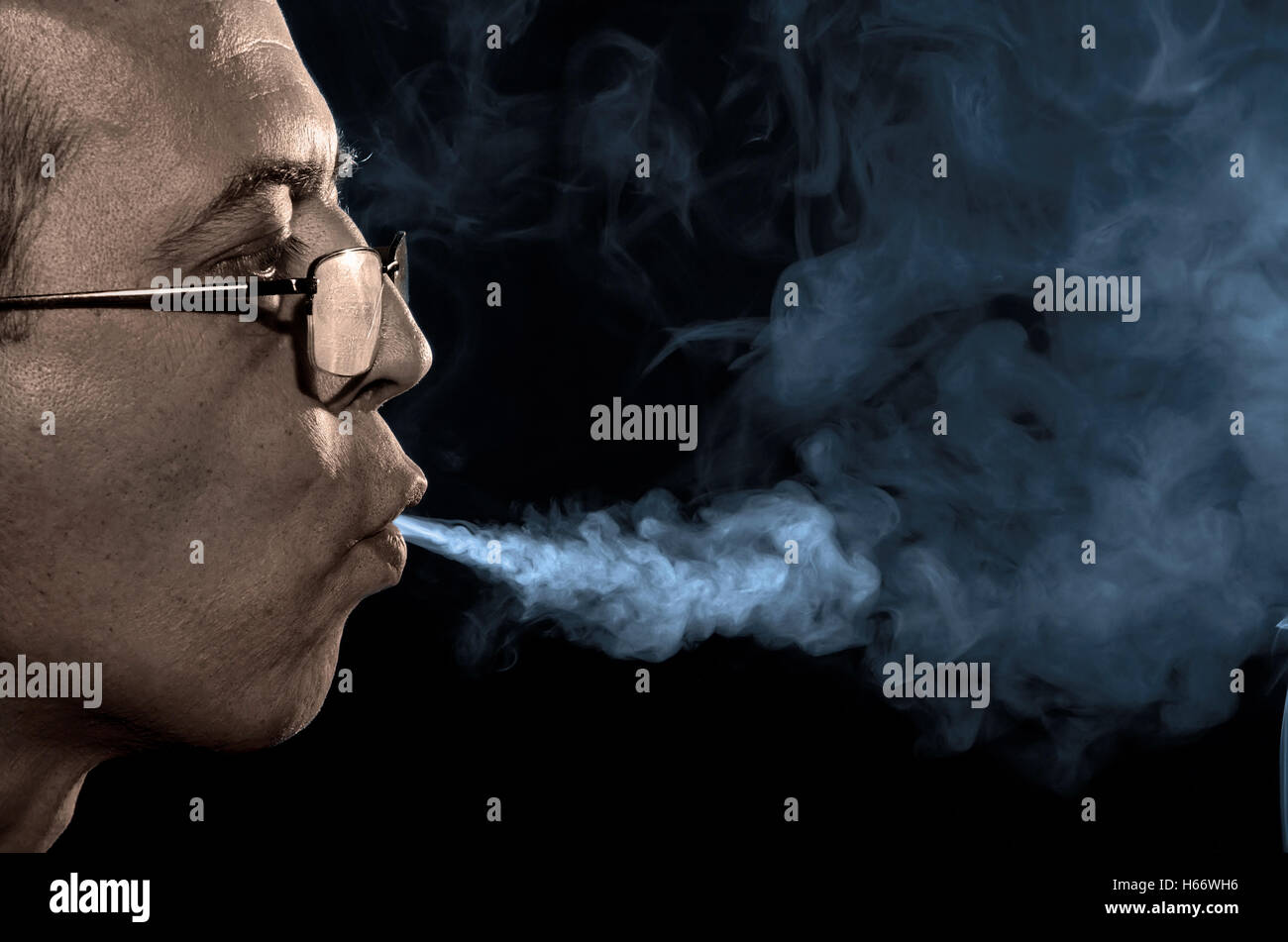 L'homme fumeur de jetting la fumée du tabac Banque D'Images