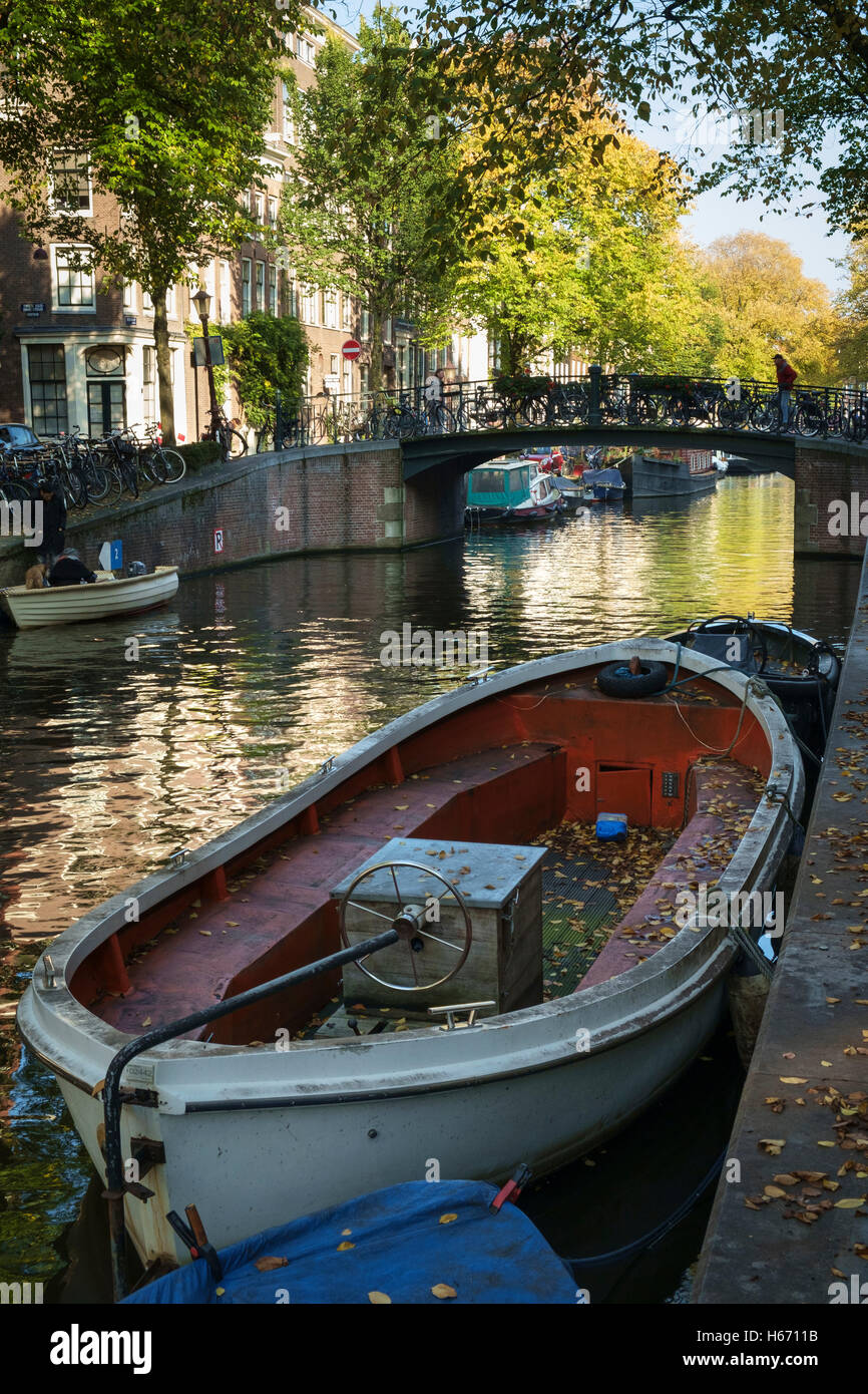 Les feuilles d'automne tombée sur un bateau amarré sur un canal à Amsterdam. Banque D'Images