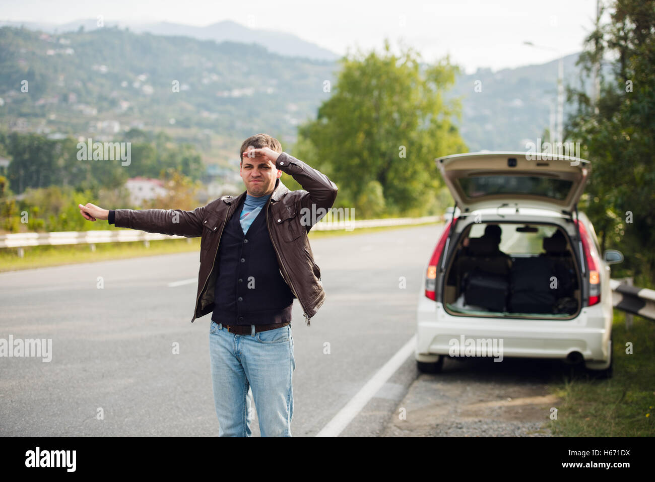 L'auto-stop - Besoin d'un lecteur. Jeune homme sur la route avec sa main posée en face de voiture Banque D'Images