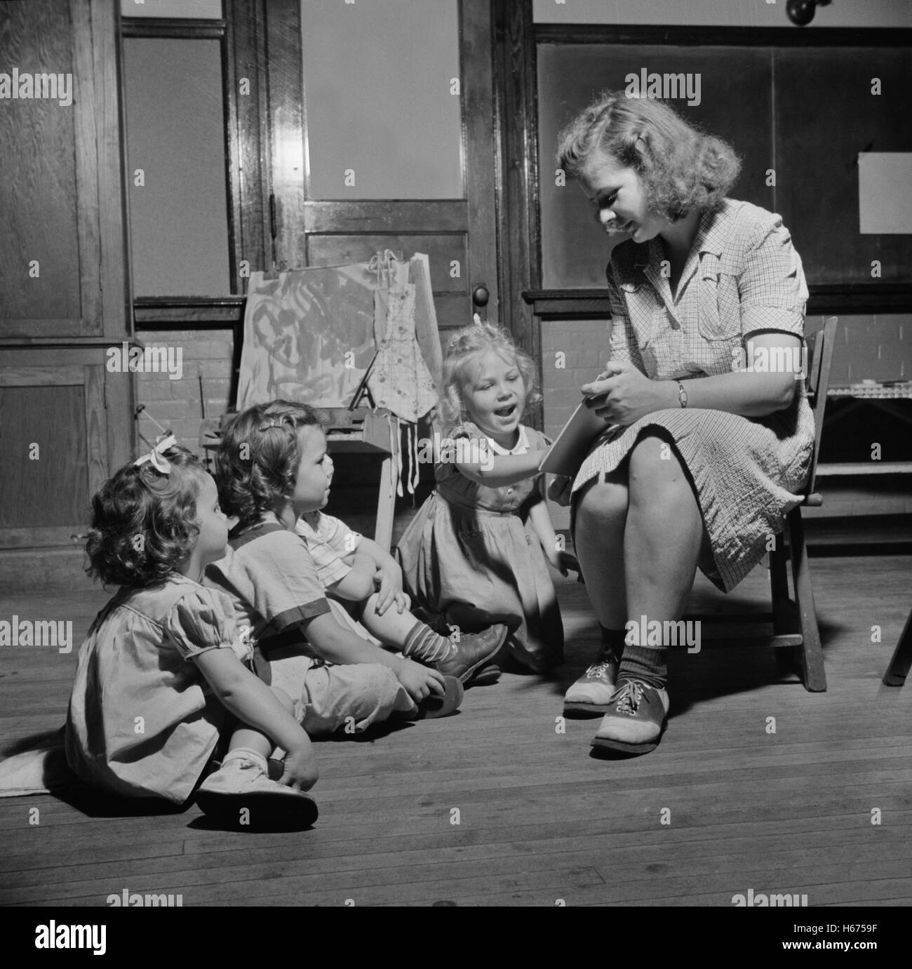 Femme lisant Histoire à trois jeunes enfants à la Garderie, New Britain, Connecticut, USA, Gordon Parks pour l'Office of War Information, Juin 1943 Banque D'Images