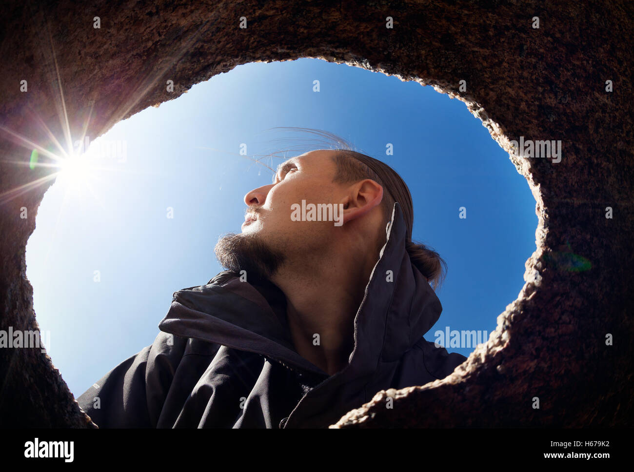 Portrait de l'homme de la grotte trou dans le desert au ciel bleu avec sun flare Banque D'Images