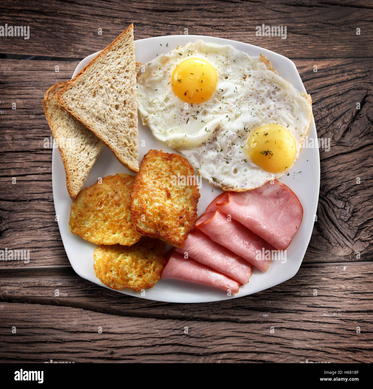 Petit déjeuner - oeufs au plat avec du jambon et des morceaux de pain. Banque D'Images