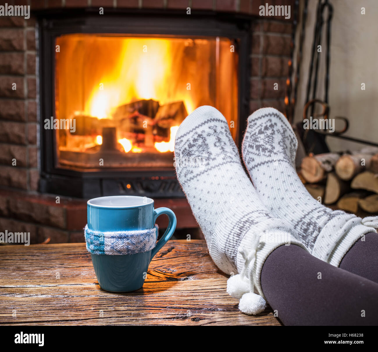 Réchauffement climatique et se reposer près de cheminée. Femme pieds près de la tasse de boisson chaude en face du feu. Banque D'Images