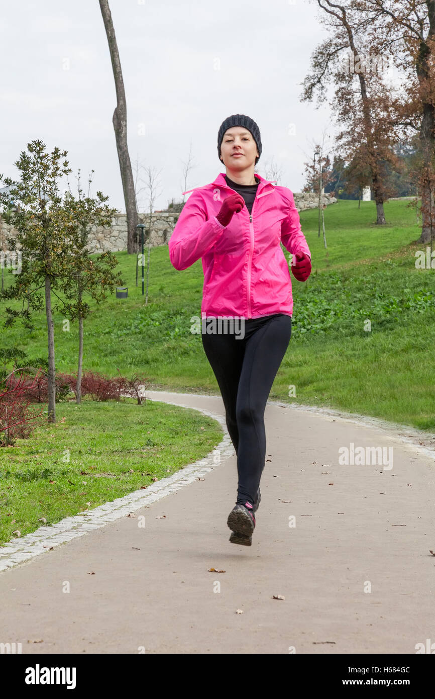 Jeune femme tournant sur une froide journée d'hiver dans un parc urbain. Banque D'Images