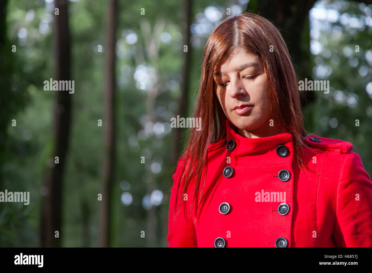 Jeune femme se sentir triste marche sur une forêt portant un manteau en hiver sous un soleil ray Banque D'Images