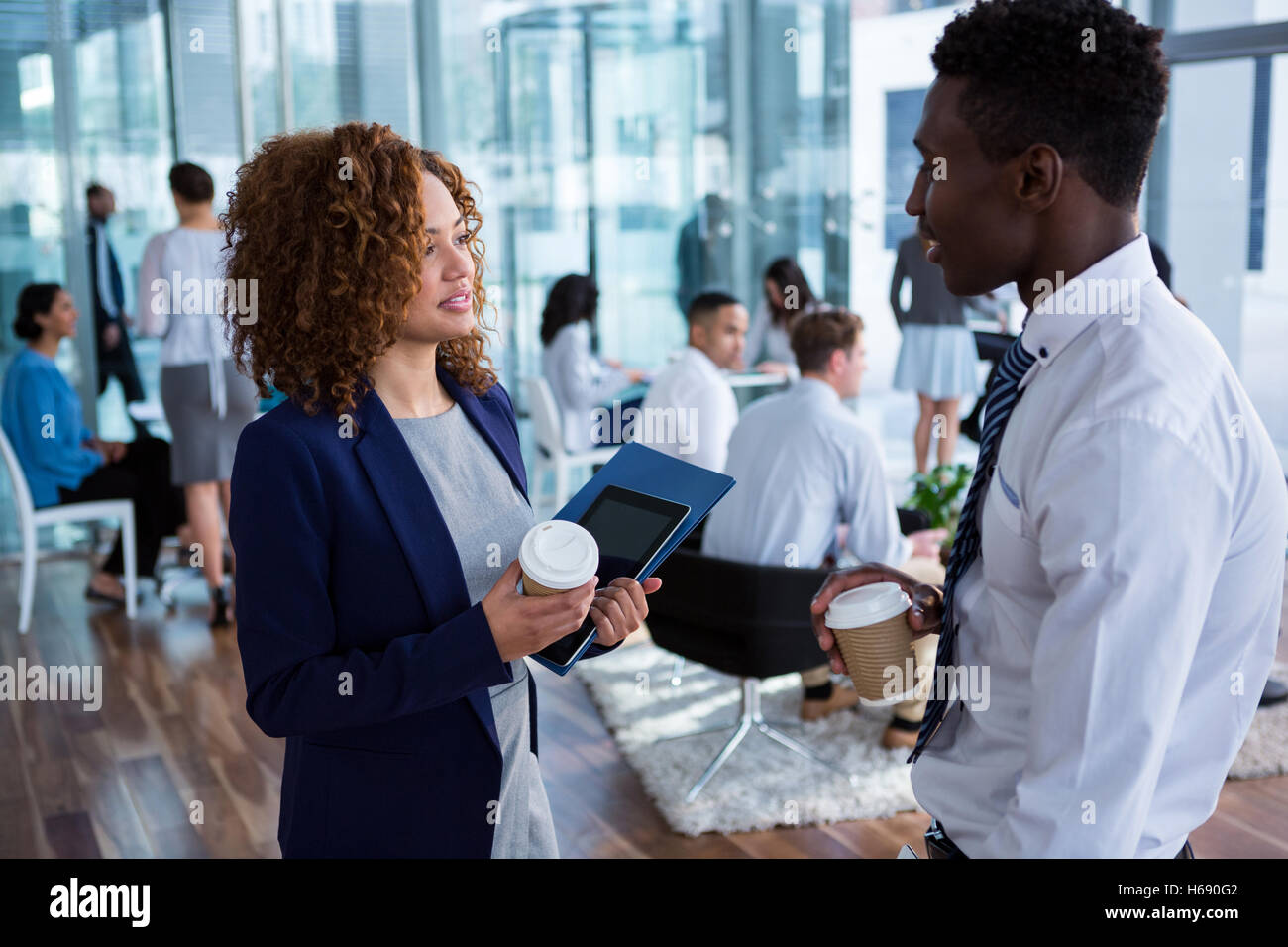 Smiling business colleagues having coffee in office Banque D'Images