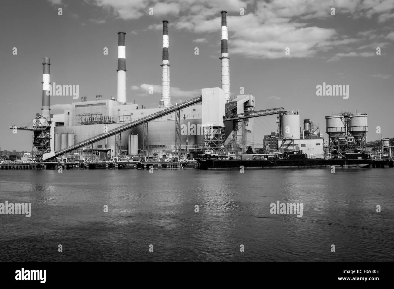 Quatre cheminée industrielle s'élever dans le ciel dans une image moitié eau et moitié en usine, comme les nuages errent dans le ciel Banque D'Images