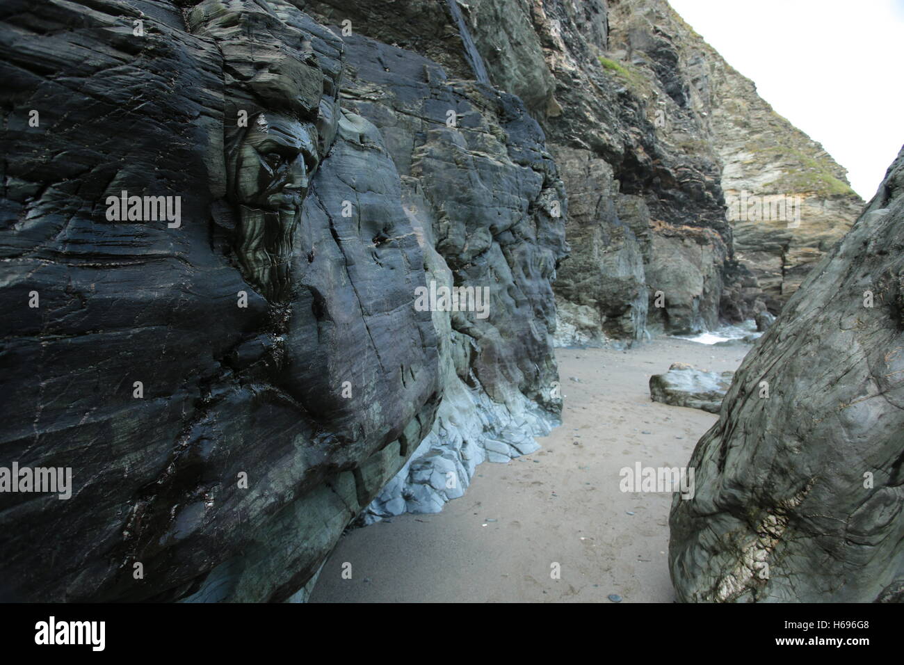 La plage de Tintagel en Cornouailles, avec des Merlins visage sculpté dans la roche. Banque D'Images